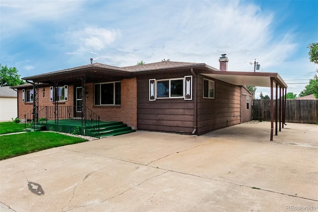 3334 W Grand Ave, Englewood, CO 80110 - view of front of house featuring a chimney, driveway, an attached carport, and brick siding