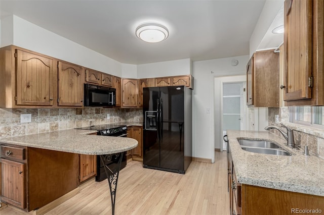 3334 W Grand Ave, Englewood, CO 80110 - kitchen featuring black appliances, decorative backsplash, light wood finished floors, and brown cabinetry