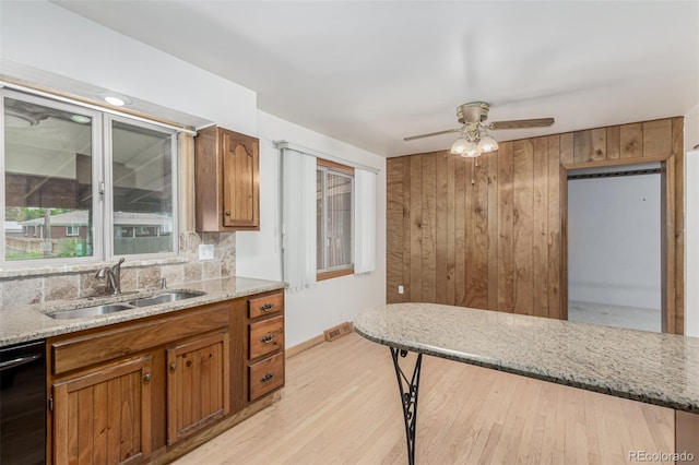 3334 W Grand Ave, Englewood, CO 80110 - kitchen with dishwasher, brown cabinets, tasteful backsplash, a ceiling fan, and wood walls