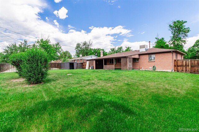 3334 W Grand Ave, Englewood, CO 80110 - rear view of property featuring brick siding, a fenced backyard, a shed, and a chimney