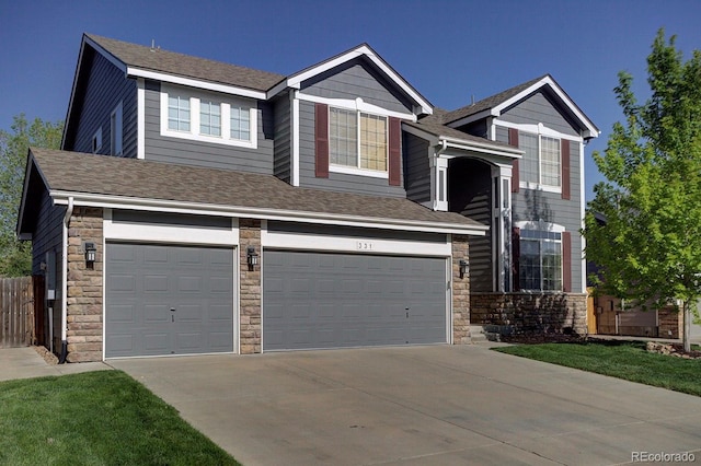view of front of home with stone siding, a garage, driveway, fence, and roof with shingles