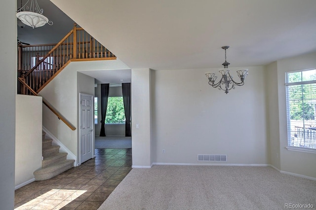 unfurnished dining area featuring a chandelier, stairway, baseboards, and carpet flooring