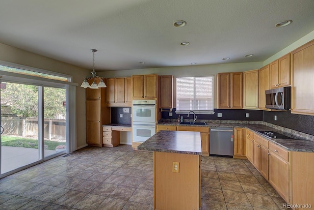 kitchen featuring stainless steel appliances, a sink, dark countertops, a kitchen island, and recessed lighting