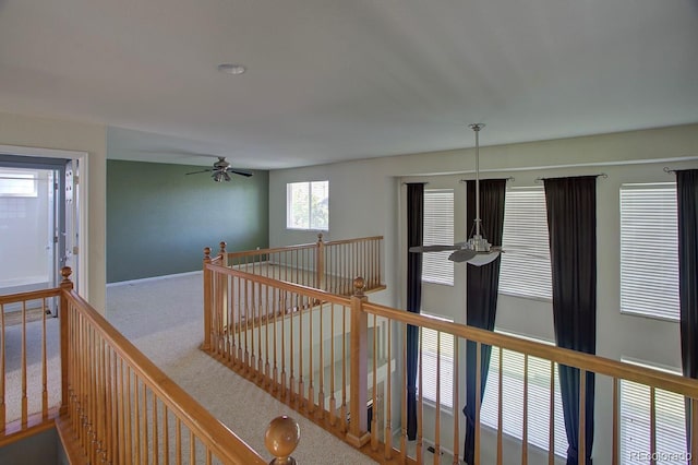 hallway featuring an upstairs landing, carpet, and baseboards