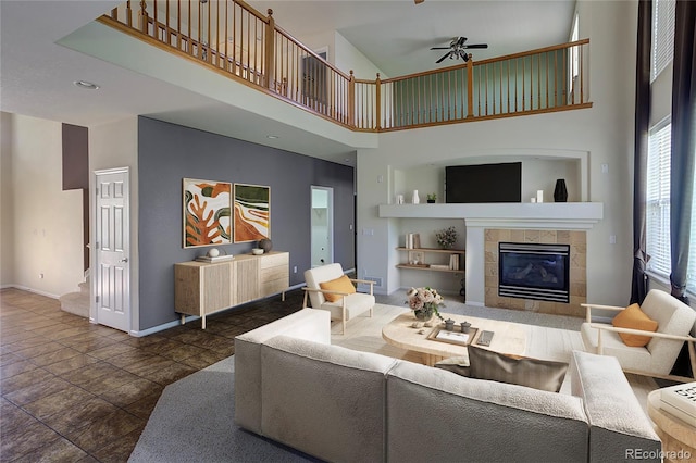 331 Las Lomas St, Brighton, CO 80601 - living room featuring a towering ceiling, ceiling fan, baseboards, and a tiled fireplace