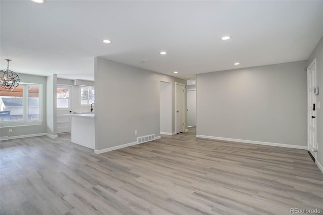 spare room with an inviting chandelier and light hardwood / wood-style flooring