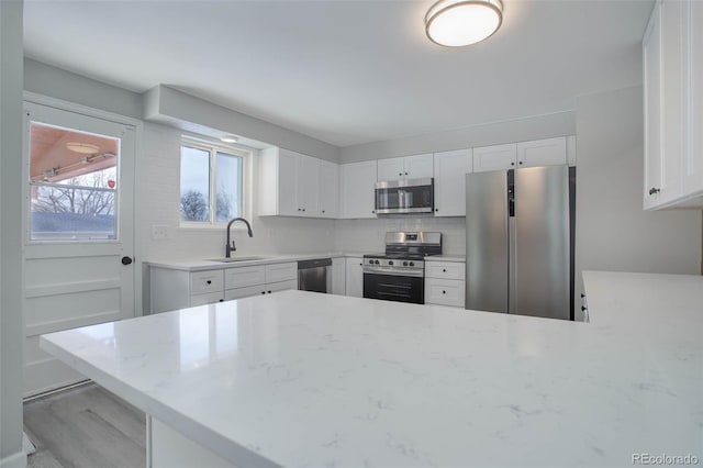 kitchen featuring stainless steel appliances, sink, white cabinets, and light stone counters