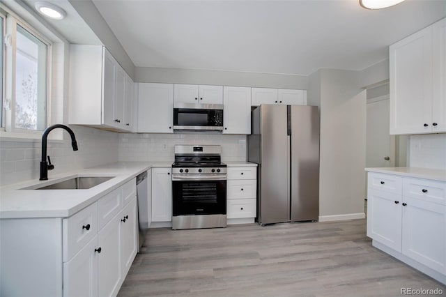 kitchen with stainless steel appliances, white cabinetry, sink, and tasteful backsplash