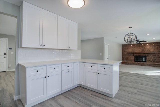 kitchen featuring pendant lighting, kitchen peninsula, light hardwood / wood-style floors, and white cabinets