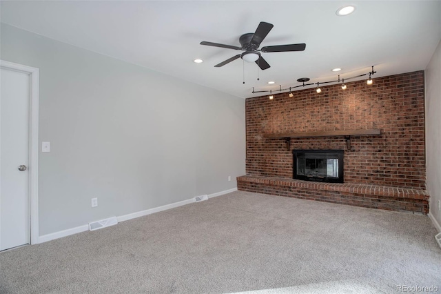 unfurnished living room featuring ceiling fan, a fireplace, rail lighting, and carpet