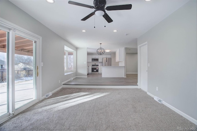 unfurnished living room with ceiling fan and carpet