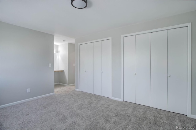 unfurnished bedroom featuring light carpet and multiple closets