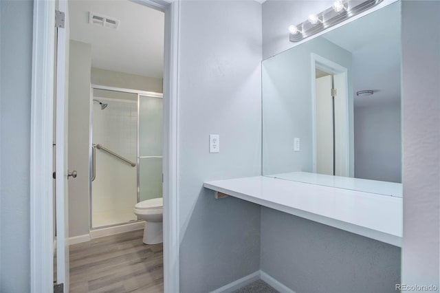 bathroom featuring an enclosed shower, vanity, wood-type flooring, and toilet