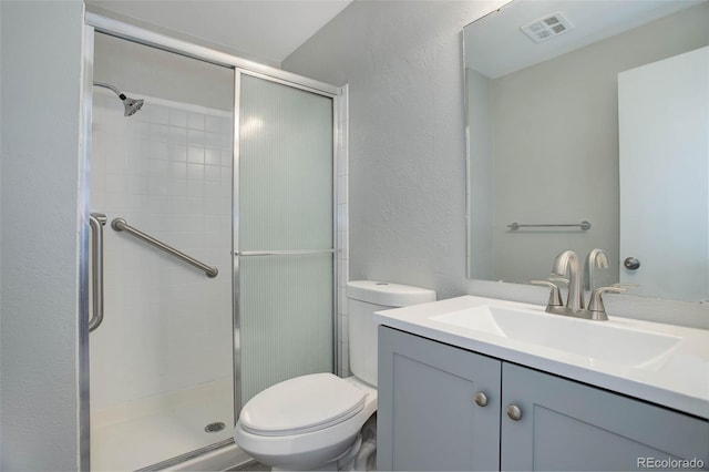 bathroom with vanity, a shower with shower door, and toilet