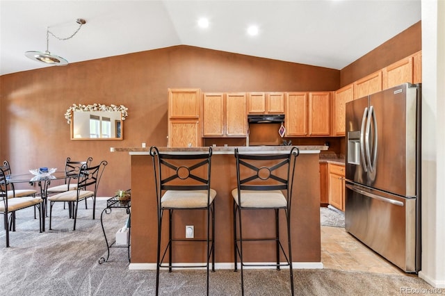 kitchen with stainless steel fridge, a kitchen island, a breakfast bar, range hood, and lofted ceiling