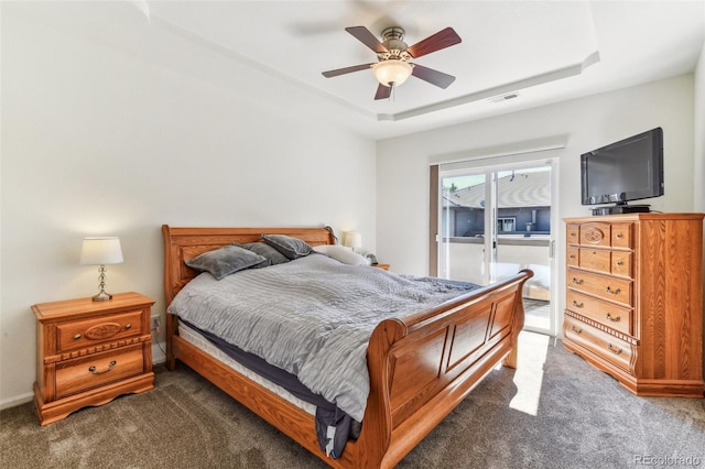 carpeted bedroom with ceiling fan, a tray ceiling, and access to outside