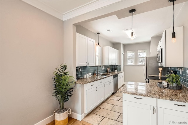 kitchen featuring appliances with stainless steel finishes, stone countertops, pendant lighting, white cabinetry, and sink