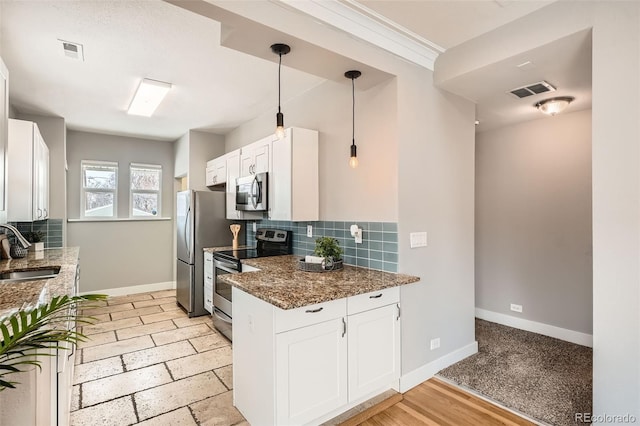 kitchen with appliances with stainless steel finishes, white cabinetry, sink, dark stone counters, and hanging light fixtures