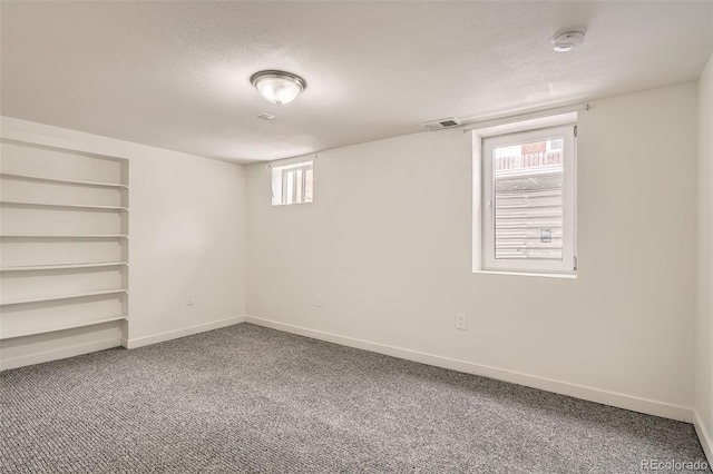 basement with built in features, carpet, and a textured ceiling