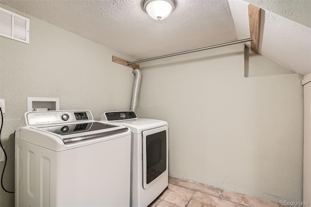 laundry area with washing machine and clothes dryer and a textured ceiling