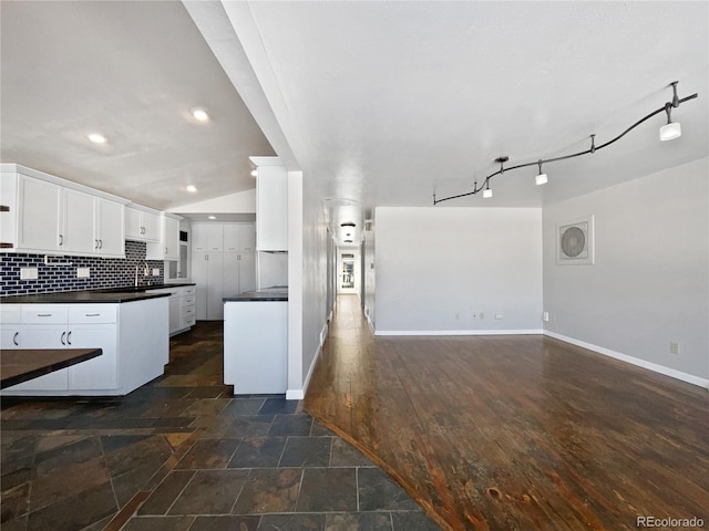 kitchen featuring sink, white cabinetry, decorative columns, tasteful backsplash, and vaulted ceiling