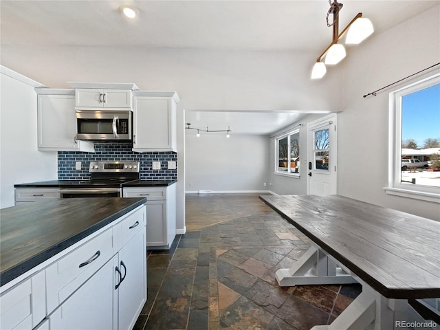 kitchen with white cabinetry, butcher block countertops, backsplash, and stainless steel appliances