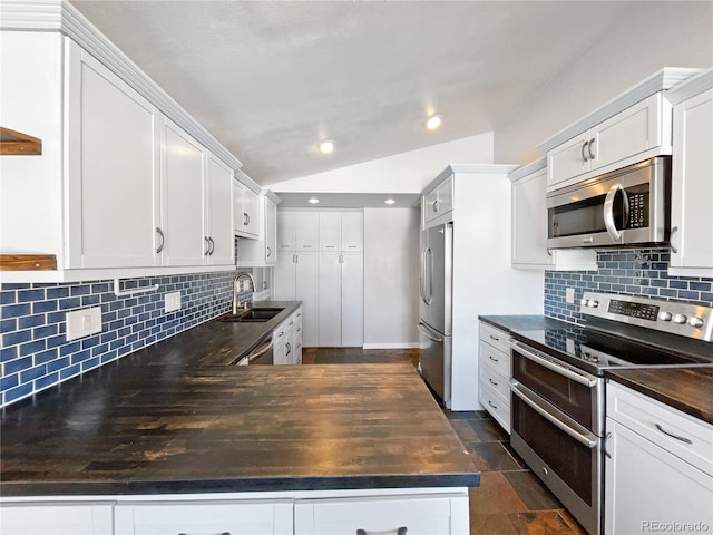 kitchen with sink, backsplash, stainless steel appliances, white cabinets, and vaulted ceiling