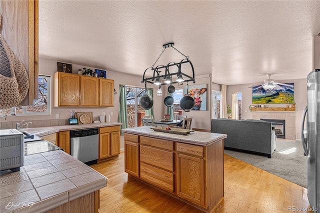 25 Tierra Casa Dr, Pueblo, CO 81005 - kitchen featuring light hardwood / wood-style flooring, a fireplace, a center island, and appliances with stainless steel finishes