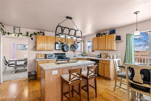 25 Tierra Casa Dr, Pueblo, CO 81005 - kitchen with a textured ceiling, light hardwood / wood-style flooring, a kitchen island, pendant lighting, and stainless steel appliances