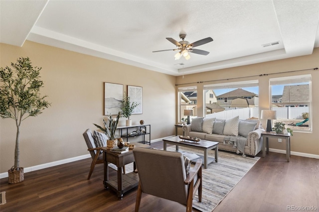 living area with dark wood-style floors, baseboards, a ceiling fan, and visible vents