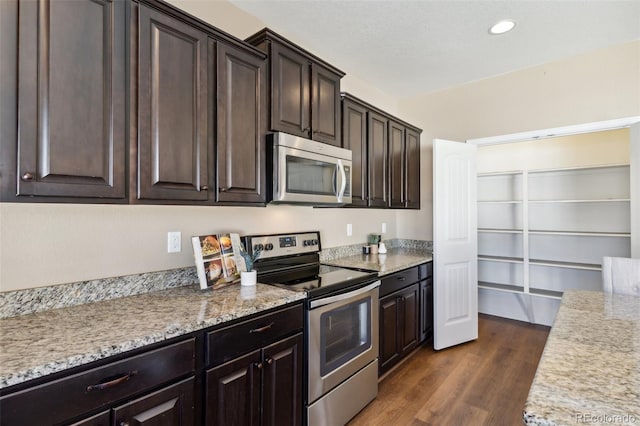kitchen with recessed lighting, dark wood finished floors, stainless steel appliances, light stone counters, and dark brown cabinets