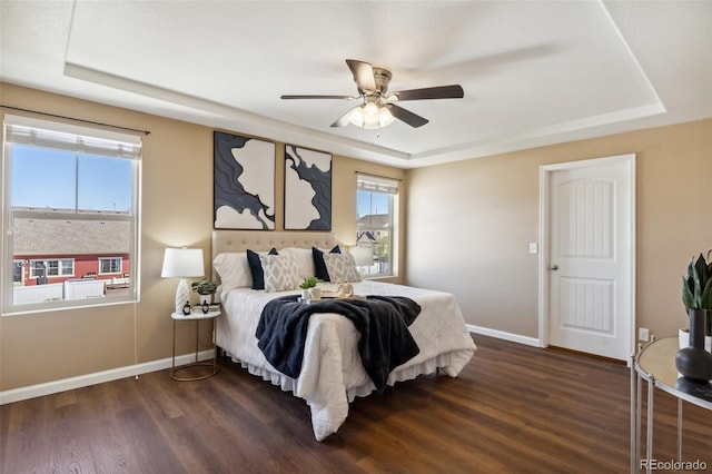 bedroom with ceiling fan, baseboards, a raised ceiling, and dark wood-style flooring