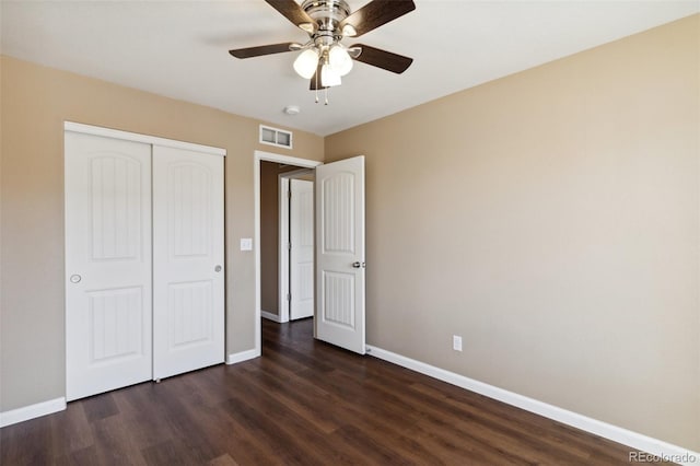 unfurnished bedroom featuring dark wood finished floors, a closet, baseboards, and visible vents