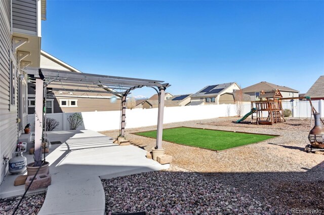 view of yard featuring a playground, a pergola, a fenced backyard, a residential view, and a patio