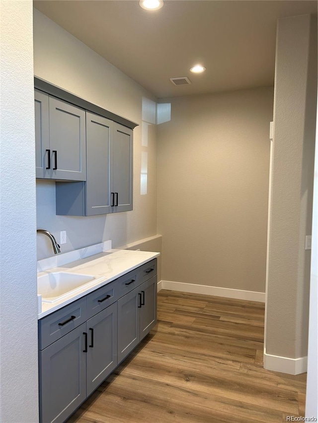 kitchen with gray cabinets, light hardwood / wood-style flooring, and sink