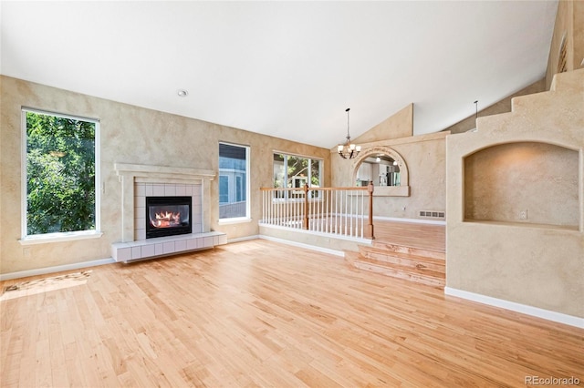6846 Edgewood Way, Highlands Ranch, CO 80130 - unfurnished living room featuring wood finished floors, a chandelier, a tiled fireplace, and lofted ceiling