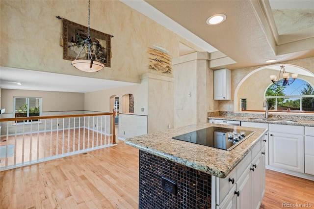 6846 Edgewood Way, Highlands Ranch, CO 80130 - kitchen with black electric cooktop, arched walkways, light stone countertops, light wood-type flooring, and recessed lighting