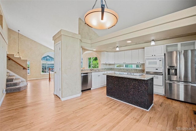 6846 Edgewood Way, Highlands Ranch, CO 80130 - kitchen featuring stainless steel appliances, light wood finished floors, white cabinets, high vaulted ceiling, and light stone counters