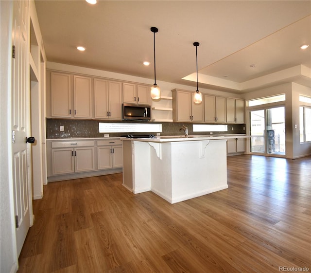 kitchen with a kitchen breakfast bar, an island with sink, pendant lighting, and dark hardwood / wood-style flooring