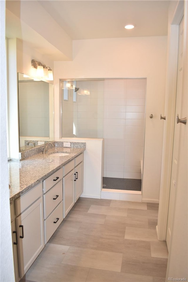 bathroom with a tile shower, hardwood / wood-style floors, and vanity