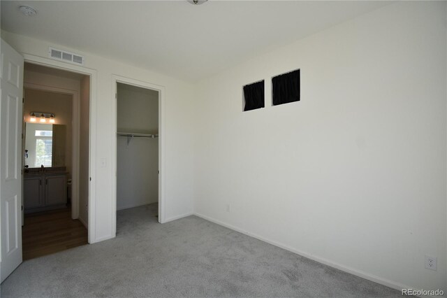 unfurnished bedroom with a spacious closet, light carpet, and a closet