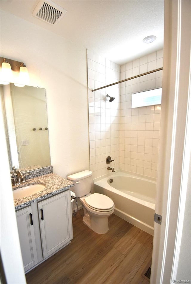 full bathroom featuring vanity, toilet, tiled shower / bath combo, and hardwood / wood-style floors