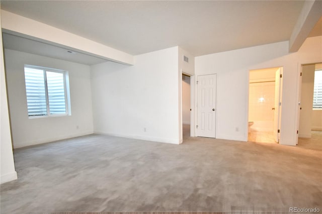 carpeted empty room with beamed ceiling