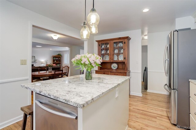 3090 S High St, Denver, CO 80210 - kitchen featuring appliances with stainless steel finishes, light wood-style flooring, light stone countertops, a center island, and pendant lighting