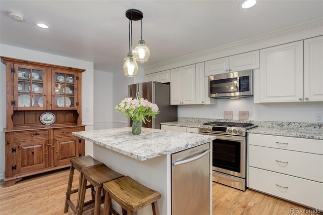3090 S High St, Denver, CO 80210 - kitchen with stainless steel appliances, light wood finished floors, a kitchen island, pendant lighting, and a kitchen breakfast bar
