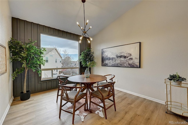 dining space with light hardwood / wood-style flooring, a chandelier, and vaulted ceiling