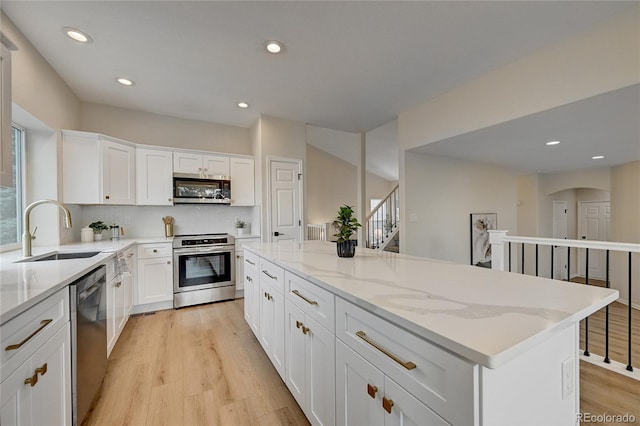 kitchen featuring a center island, sink, stainless steel appliances, decorative backsplash, and white cabinets