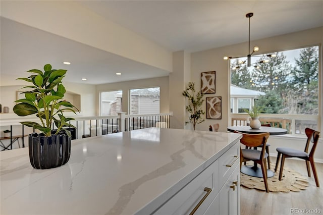 kitchen featuring light stone countertops, white cabinets, a chandelier, and decorative light fixtures