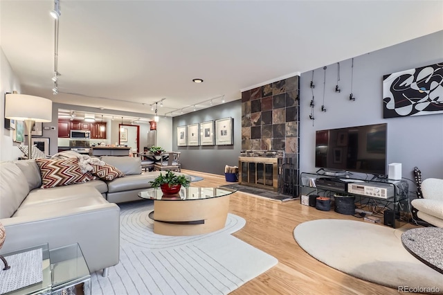 living room featuring track lighting, a tile fireplace, and wood-type flooring