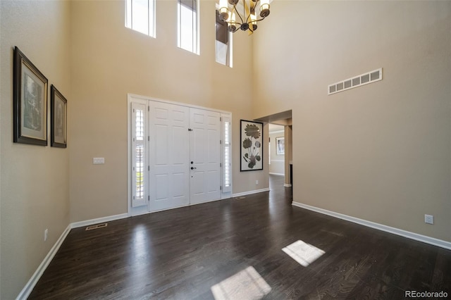 entryway featuring a towering ceiling, a wealth of natural light, dark hardwood / wood-style flooring, and a notable chandelier